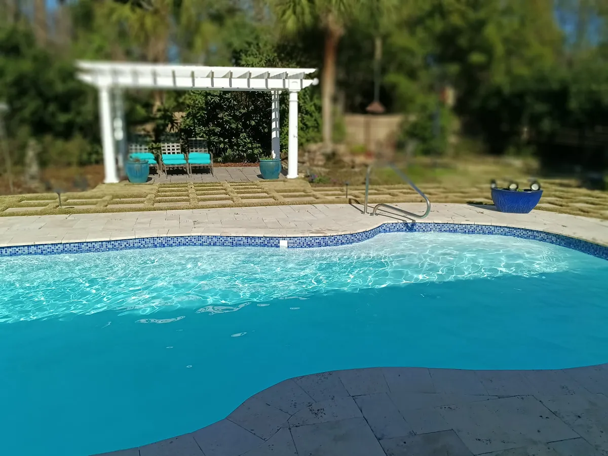 Crystal clear pool with blue mosaic tile and white pergola in Charleston SC